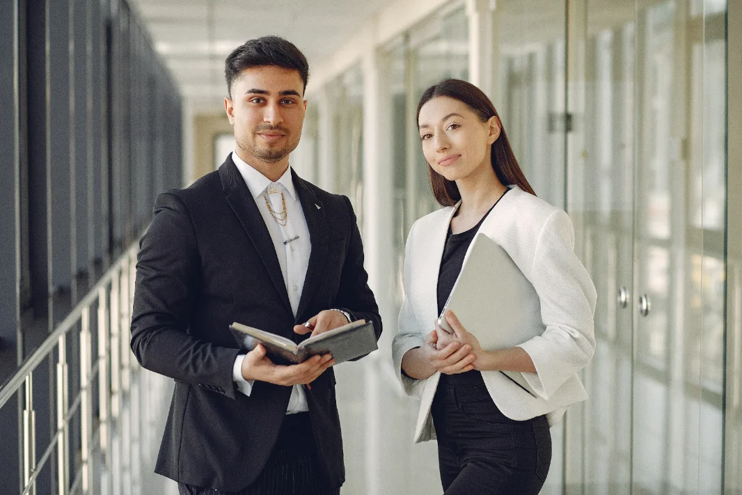 Two BrightHire colleagues in business attire standing in an office corridor